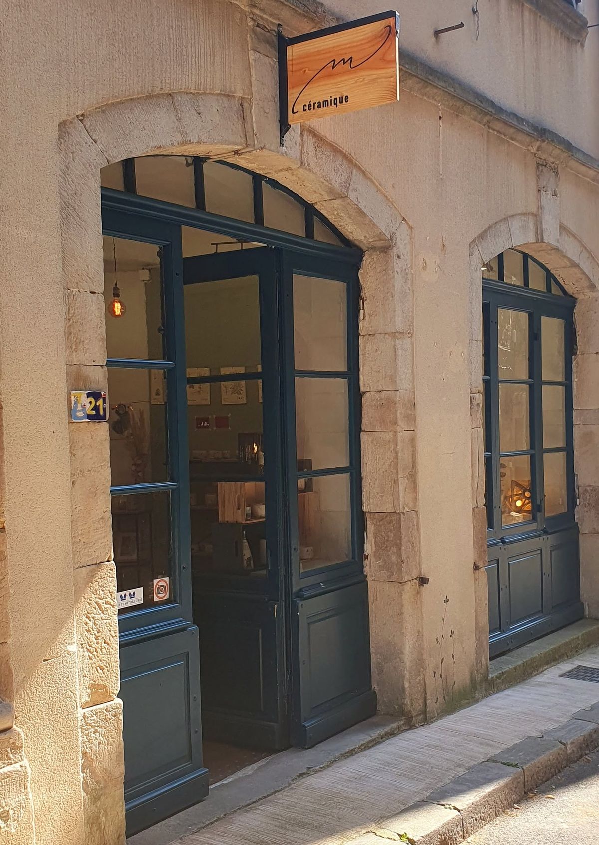 Portes vitrées bleues de la boutique M Céramique sous leurs arches de pierre, Grand Rue à Joyeuse