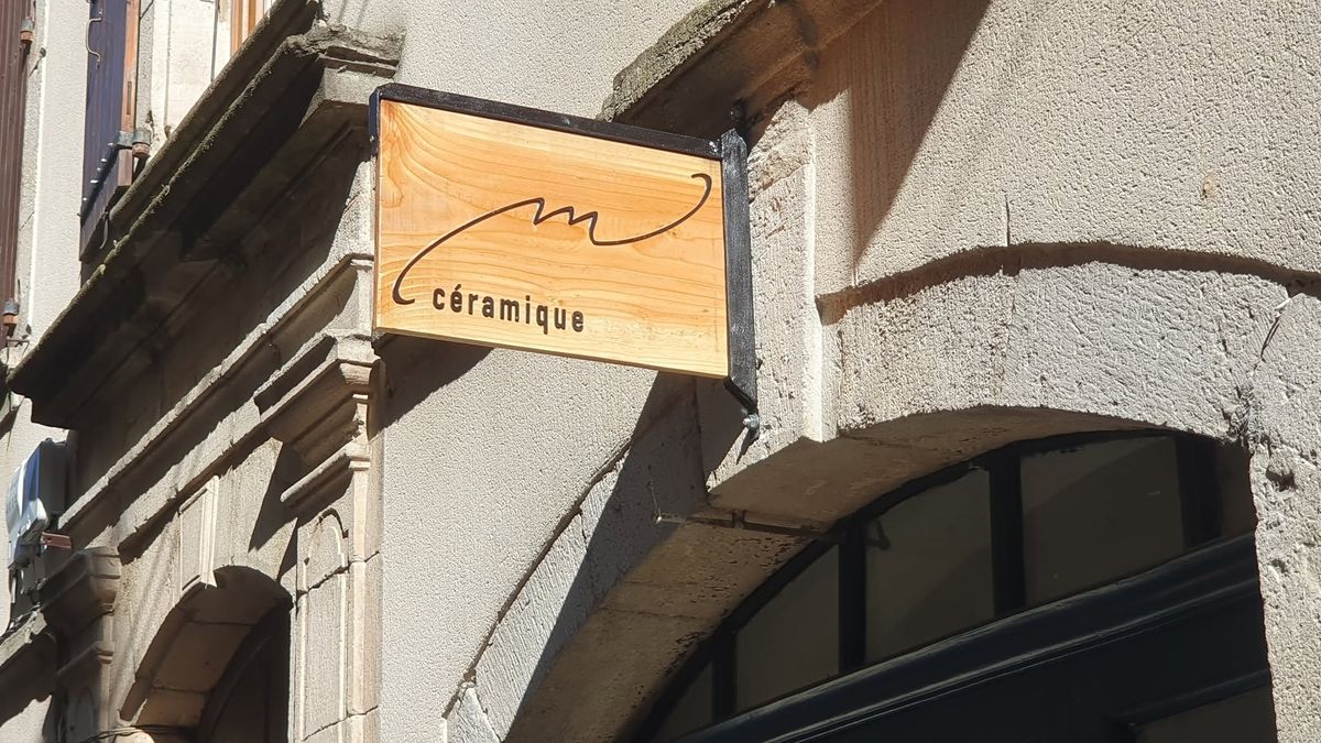 Enseigne en bois M Céramique accrochée à la façade de pierre, Grand Rue à Joyeuse